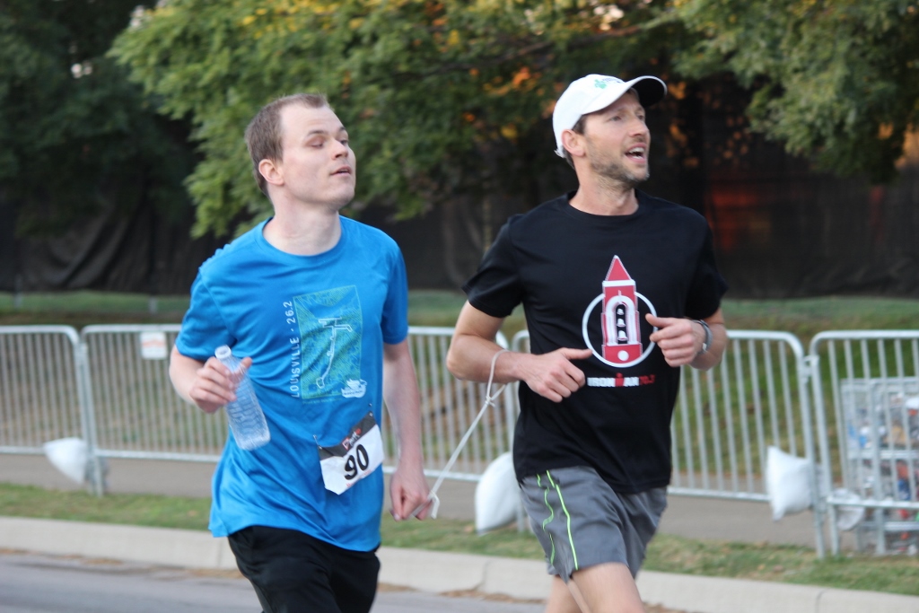 A male runner who is blind is tethered to a sighted male runner.