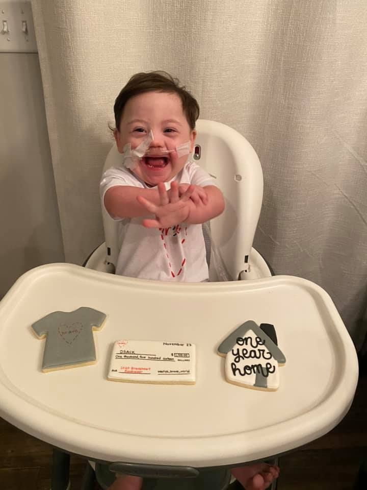 Little Wally sits at his high chair, smiling happily, with cookies displayed in front of him celebrating his year anniversary of being home from the hospital.