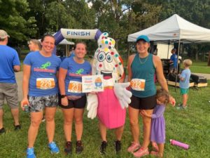 Group of runners smiling and they are with someone dressed up as a cupcake.