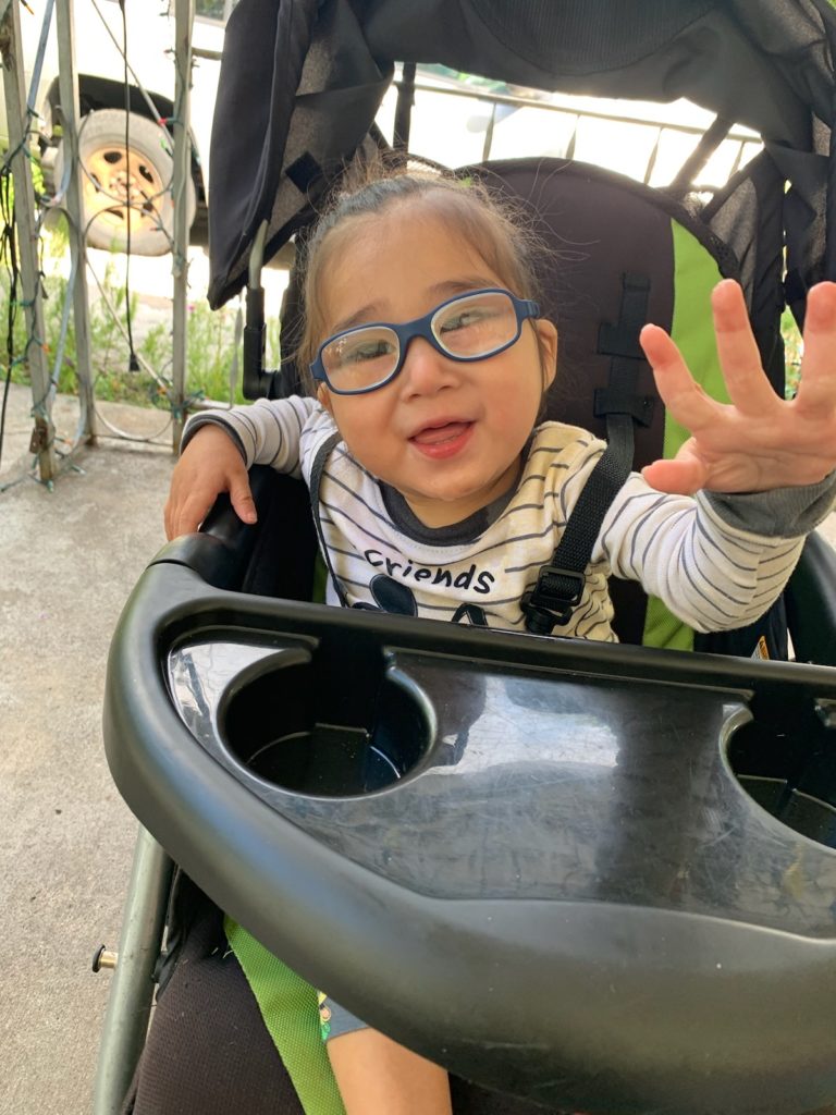 Odin sitting in a stroller laughing while reaching at the camera