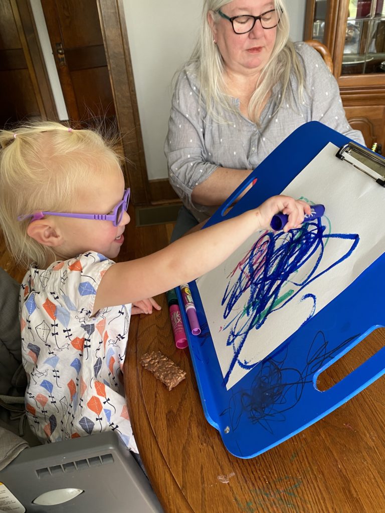 Avelyn drawing on a clip board tilted at a 45 degree angle