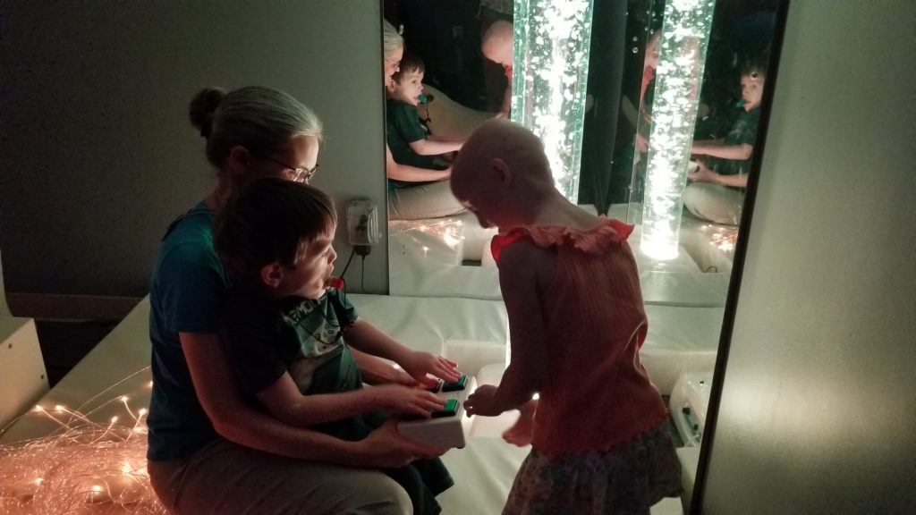 Children in a dark room with lighted bubble tubes