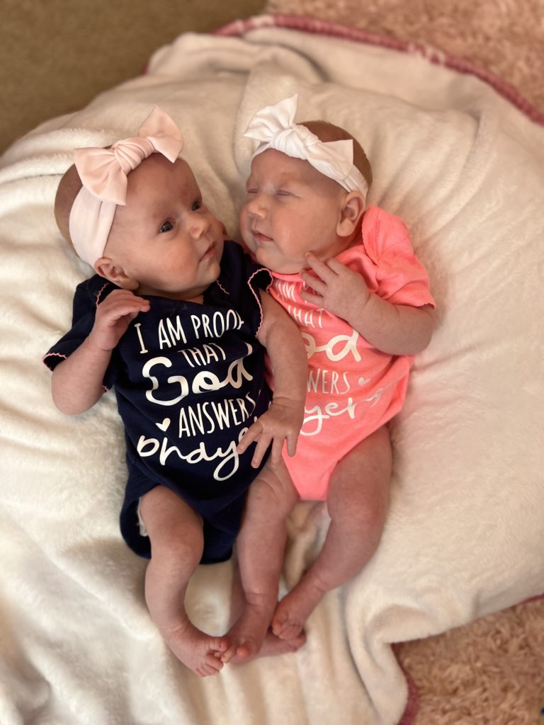 Twin infant girls cuddled up next to each other