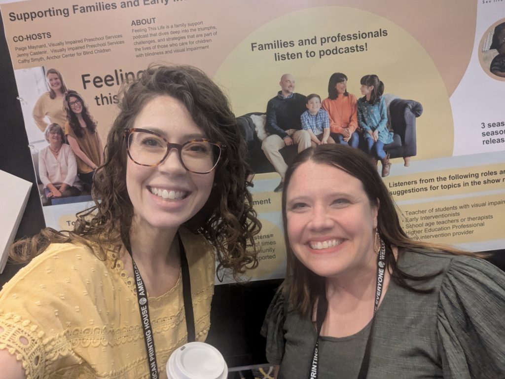 Two women in front of a poster, smiling.