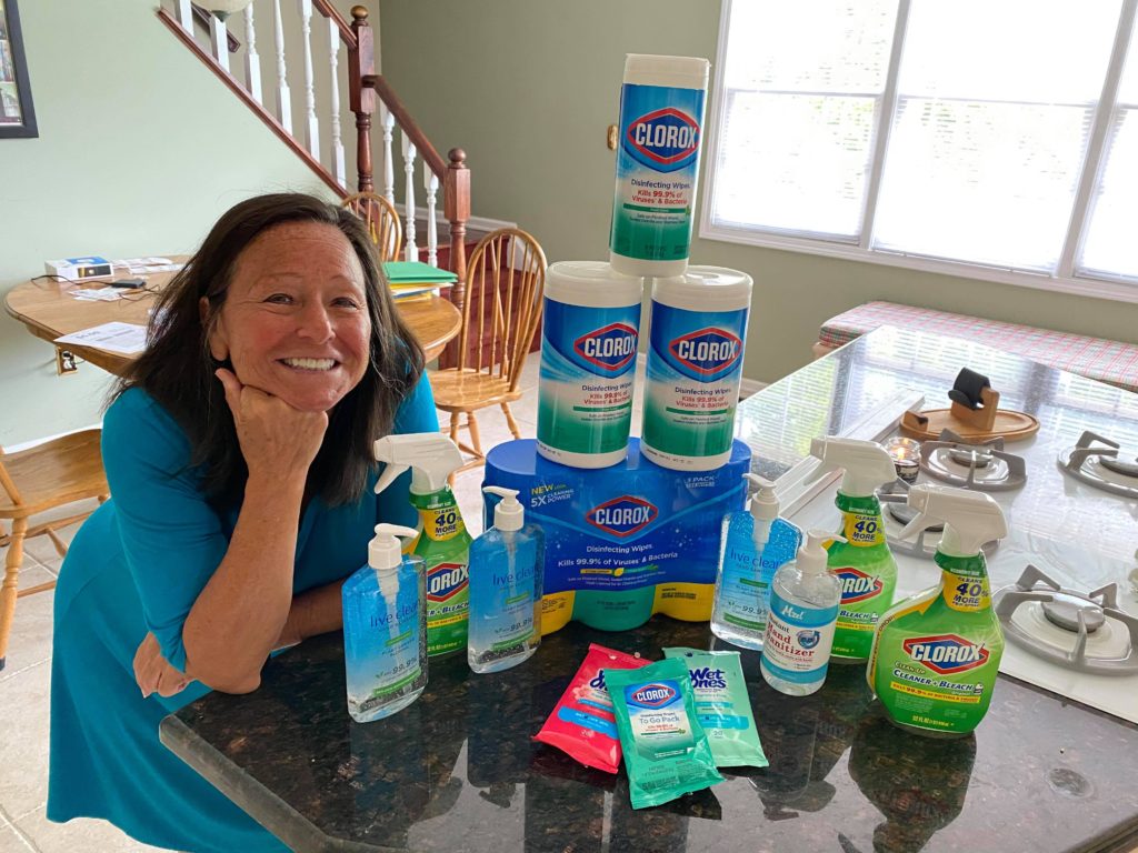 A woman with dark hair is leaning on a counter next to various cleaning supplies used as donations to VIPS.