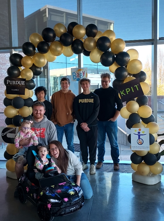 group photo of Brynn in her car with the team that made it