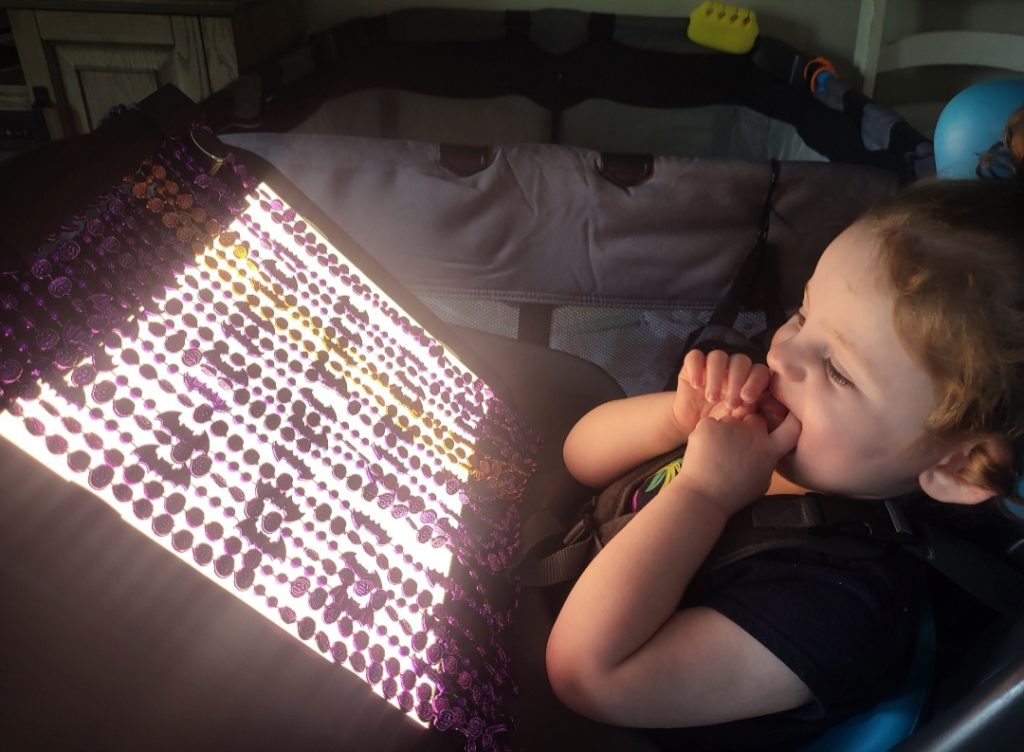 A child looks at a lightbox with beads over it