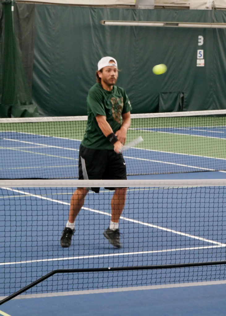 A pickleball player returns a volley.