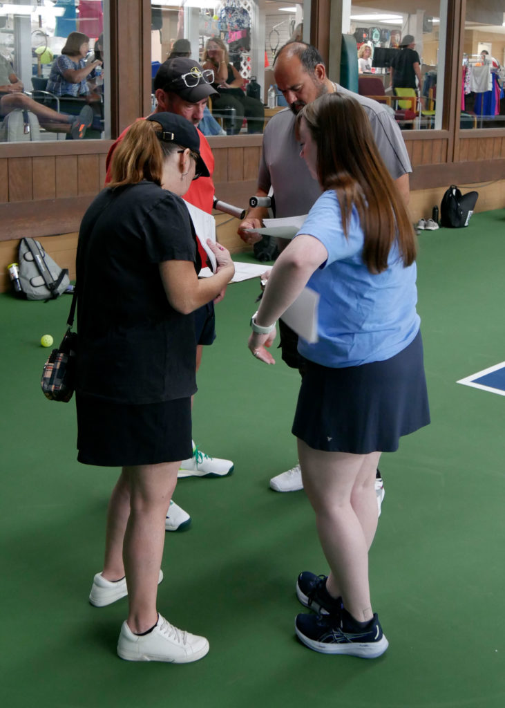 Pickleball tournament volunteers meet before play begins.