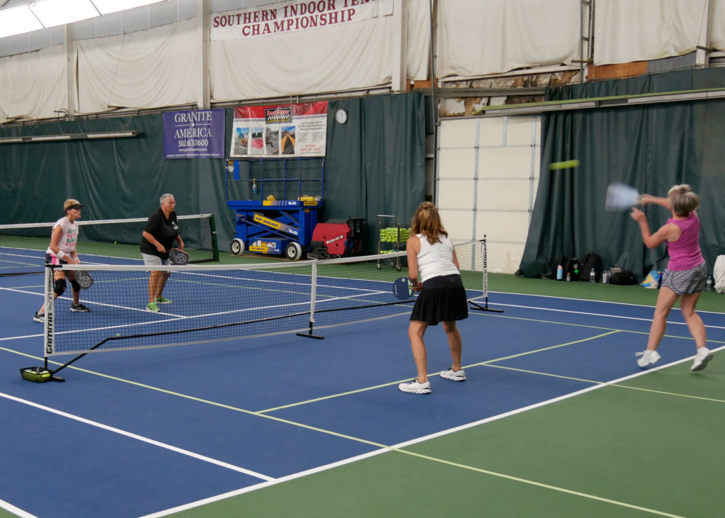 Pickleball doubles teams playing.