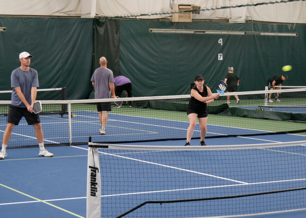 Pickleball doubles teams playing.