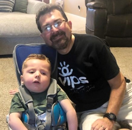 A man with glasses sits near a child in a seat