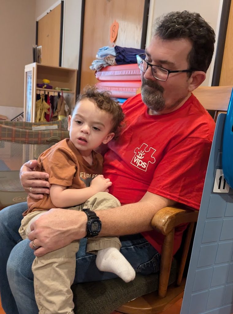 A man with a beard and glasses is holding a child