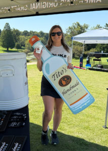 The Tito's bartender poses for a photo with a large cutout of a Tito's Handmade Vodka bottle.
