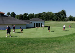 A group of men practice putting before the golf scramble begins.