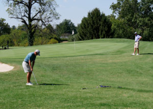 A man chipping while his team member watches.