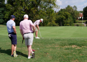 A man puts while his two teammates watch.