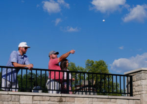 A man throws a golf ball of the patio onto the green during the Ball Toss contest.