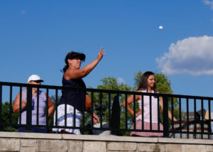 A woman throws a golf ball of the patio onto the green during the Ball Toss contest.