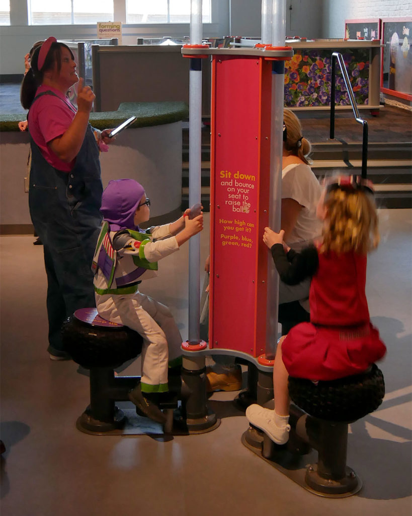 A boy and a girl bounce on an interactive display at the Kentucky Science Center while Ashley Emmons speaks to a parent.