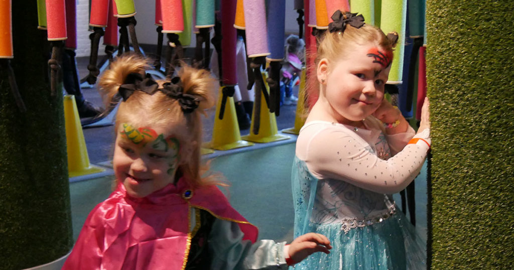 Two girls pause chasing each other through the hanging pool noodles at the Kentucky Science Center.