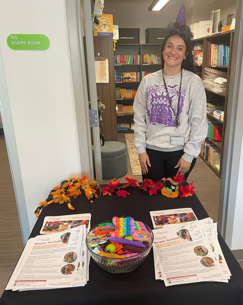 A woman representing Crossroads poses for a photo behind their table at the FRC.