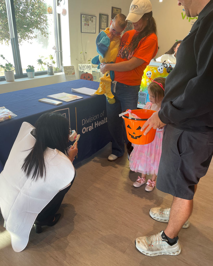 Families get a tooth-brushing demonstration at the Oral Health Division of the Indiana Department of Health table.