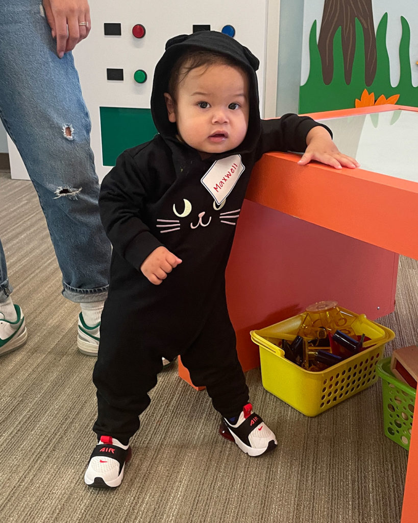 A small boy wearing a cat costume poses for a photo.