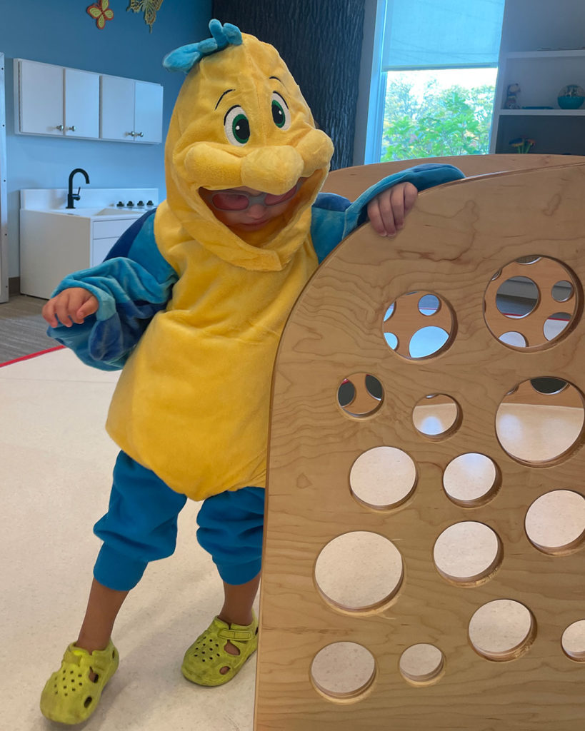 A boy in a chicken costume plays in the activity room at the FRC.
