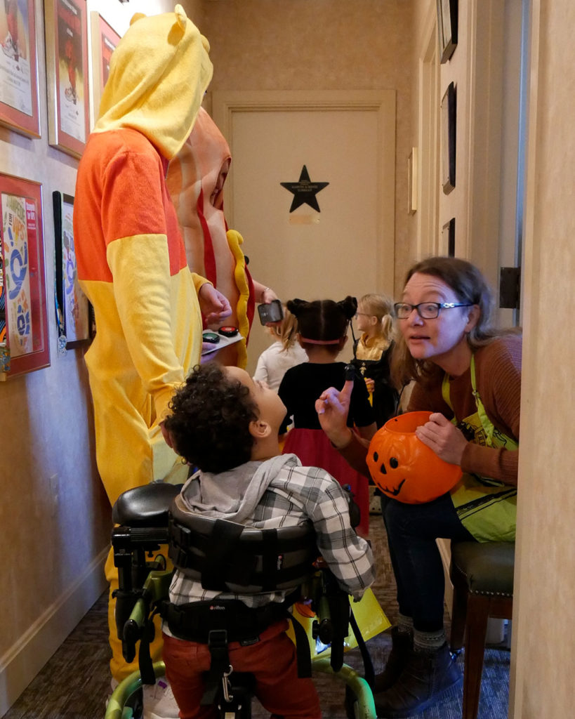 A small boy in a mobility chair gets a finger puppet toy from Miss Christina.