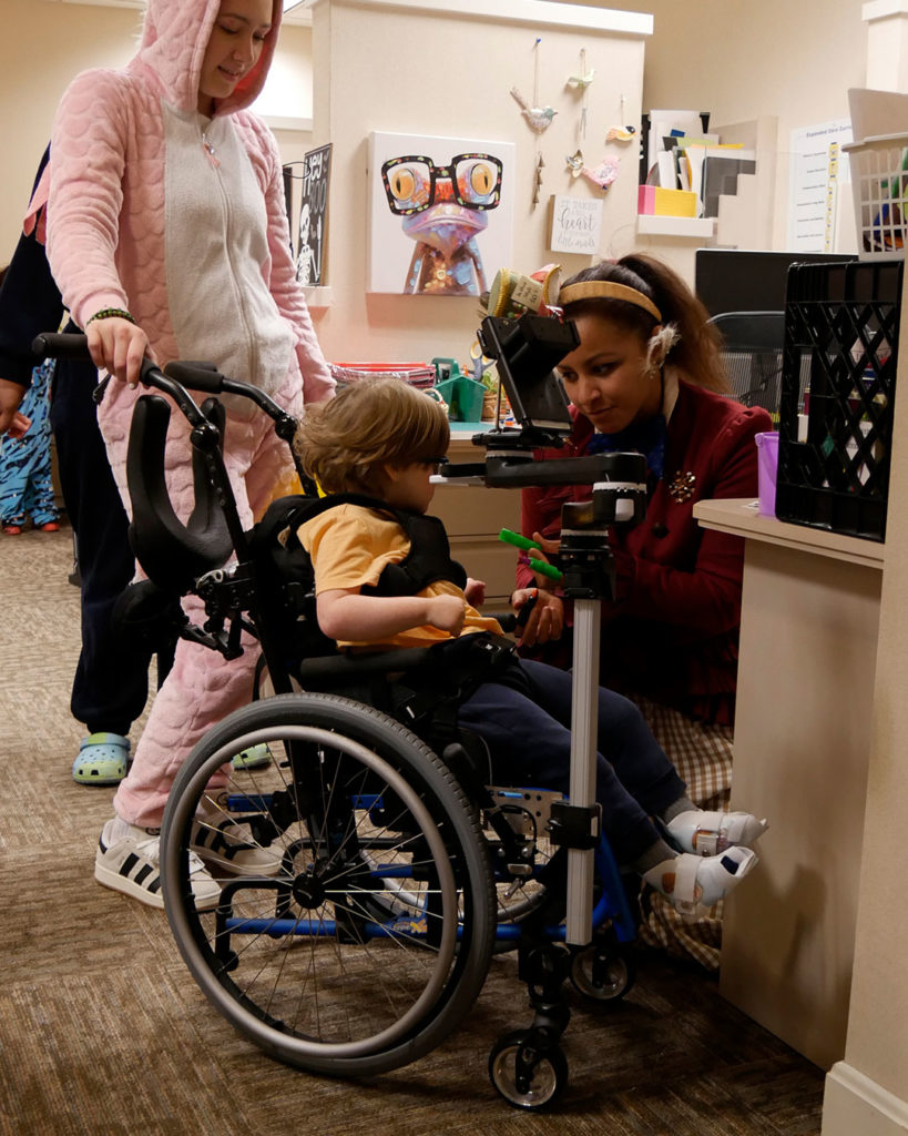 Miss Rebecca hands out zombie fingers to a small boy in a wheelchair.