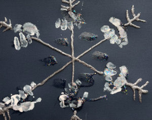 A six point child-made snowflake created with glitter glue and inward-pointing chevrons on the ends on black construction paper. The spines are decorated with handprints in white ink.