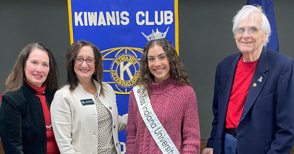 Diana Fellure, Sheila Klopfenstein, Alexxys Standish, and Allen Pease pose for a photo in front of the Kiwanis Club of Bloomington banner.
