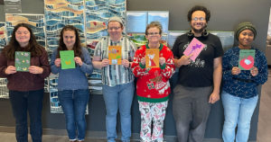 Six volunteers pose for a photo in the FRC while holding some of the welcome cards they made.