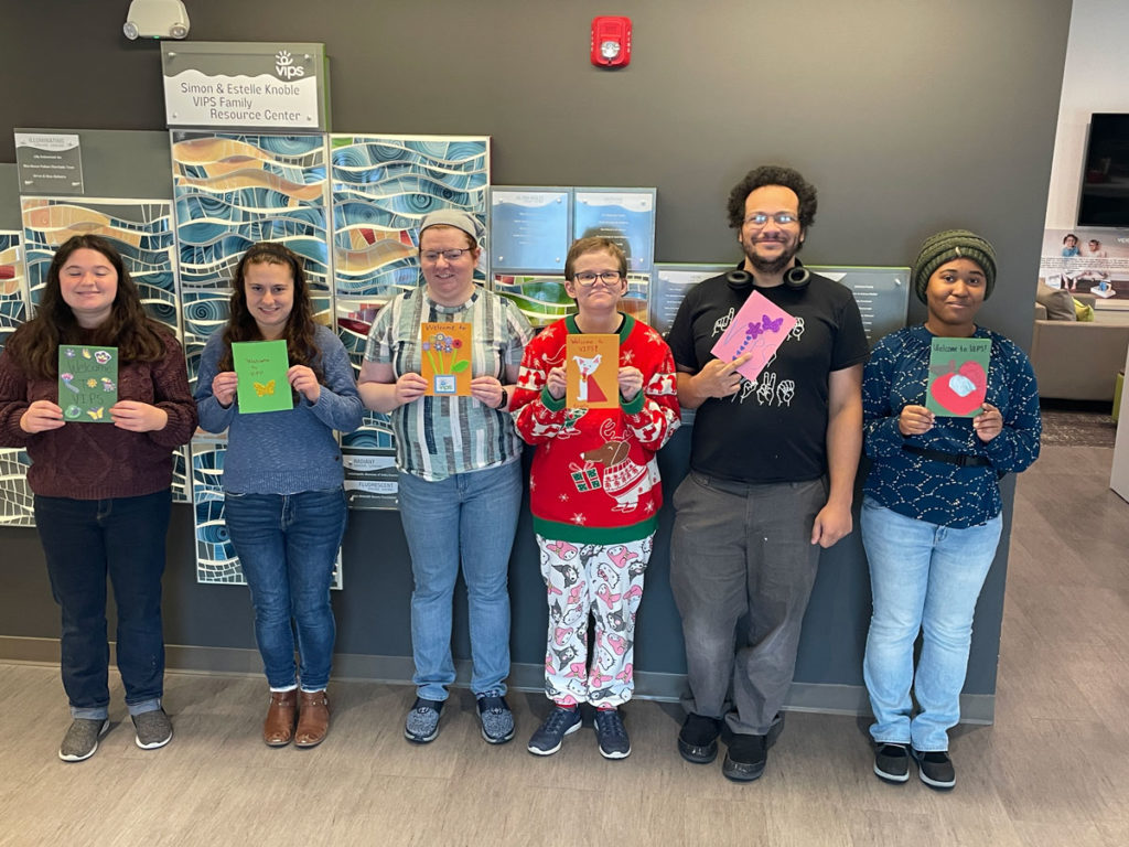 Six volunteers pose for a photo in the FRC while holding some of the welcome cards they made.