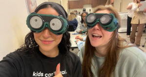 Two female OT students take a selfie while wearing simulation goggles.