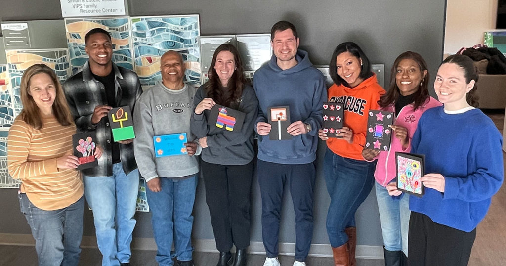 Volunteers from the NCAA PR team pose for a photo with the cards they made.