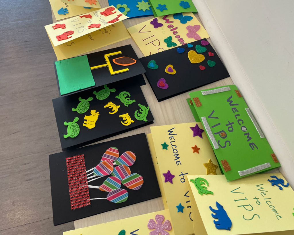 "Welcome to VIPS" cards made by volunteers from the NCAA PR team are displayed on a table.