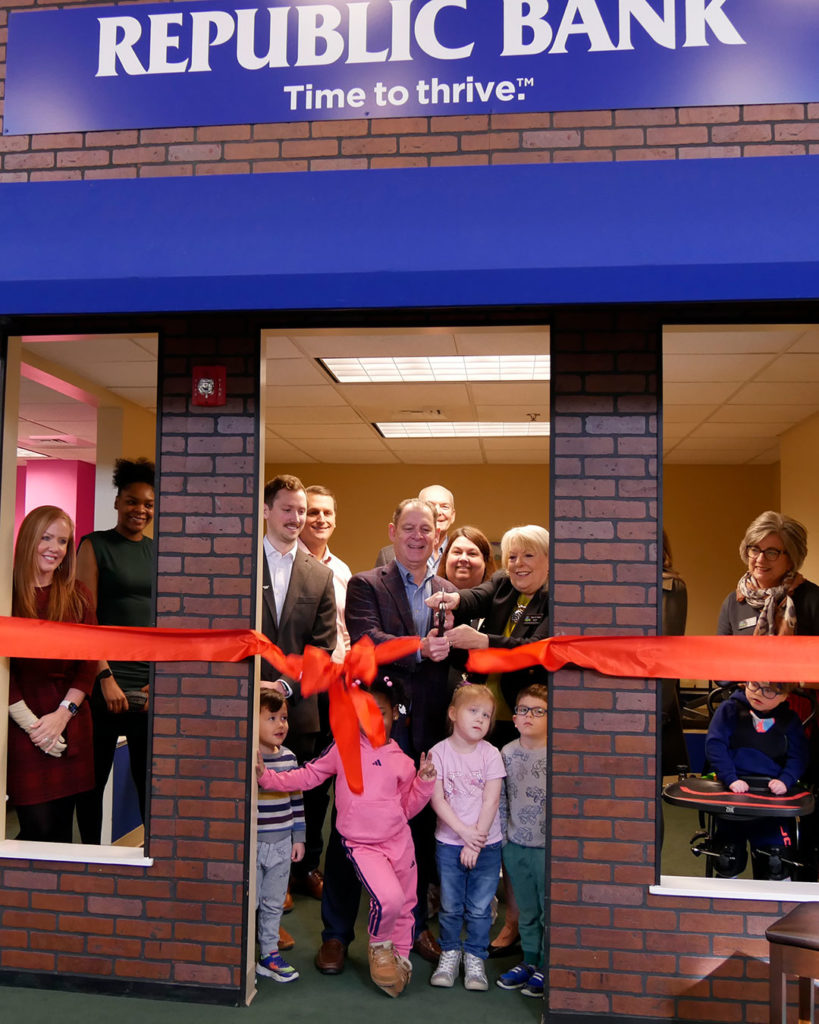The teams from Republic Bank and VIPS, along with the preschoolers, cut the red ribbon.