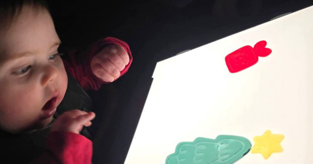 Myles is focusing intently on brightly colored window clings on a lightbox.