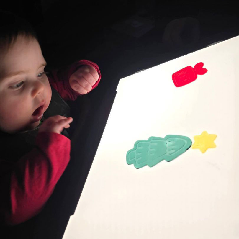 Myles is focusing intently on brightly colored window clings on a lightbox.