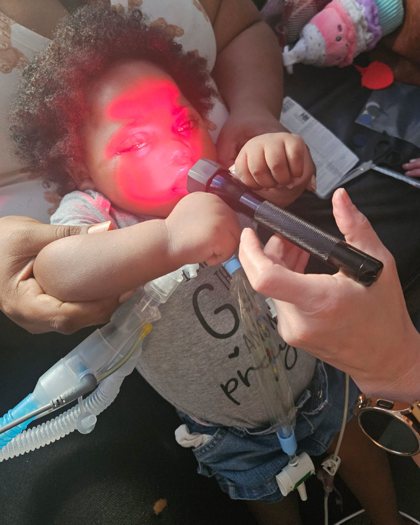 Kilani lies in her mother's lap and touches the red light she has been tracking.