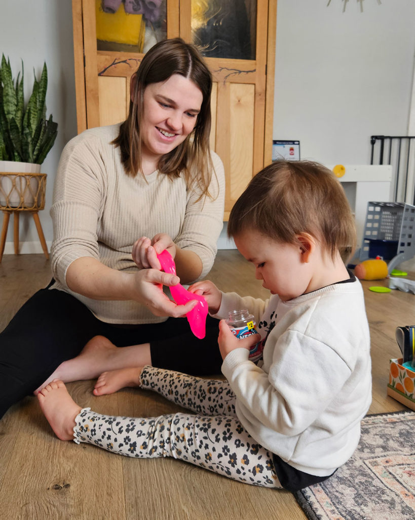 Penelope sits in the floor and exams a slime jar.