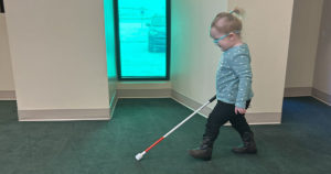 Roxanne is walking across the stage in Kids Town using her white cane.