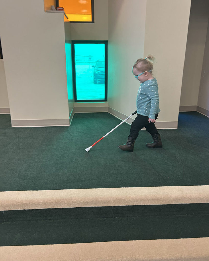 Roxanne is walking across the stage in Kids Town using her white cane.