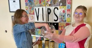 Christina Welsh draws the name of the Bourbon Raffle winner from a bowl held by Justine Aycock.