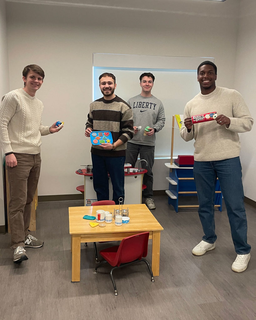 Four young men from Mercy Road Church pose for a photo with items from the kids' playroom at the Family Resource Center.