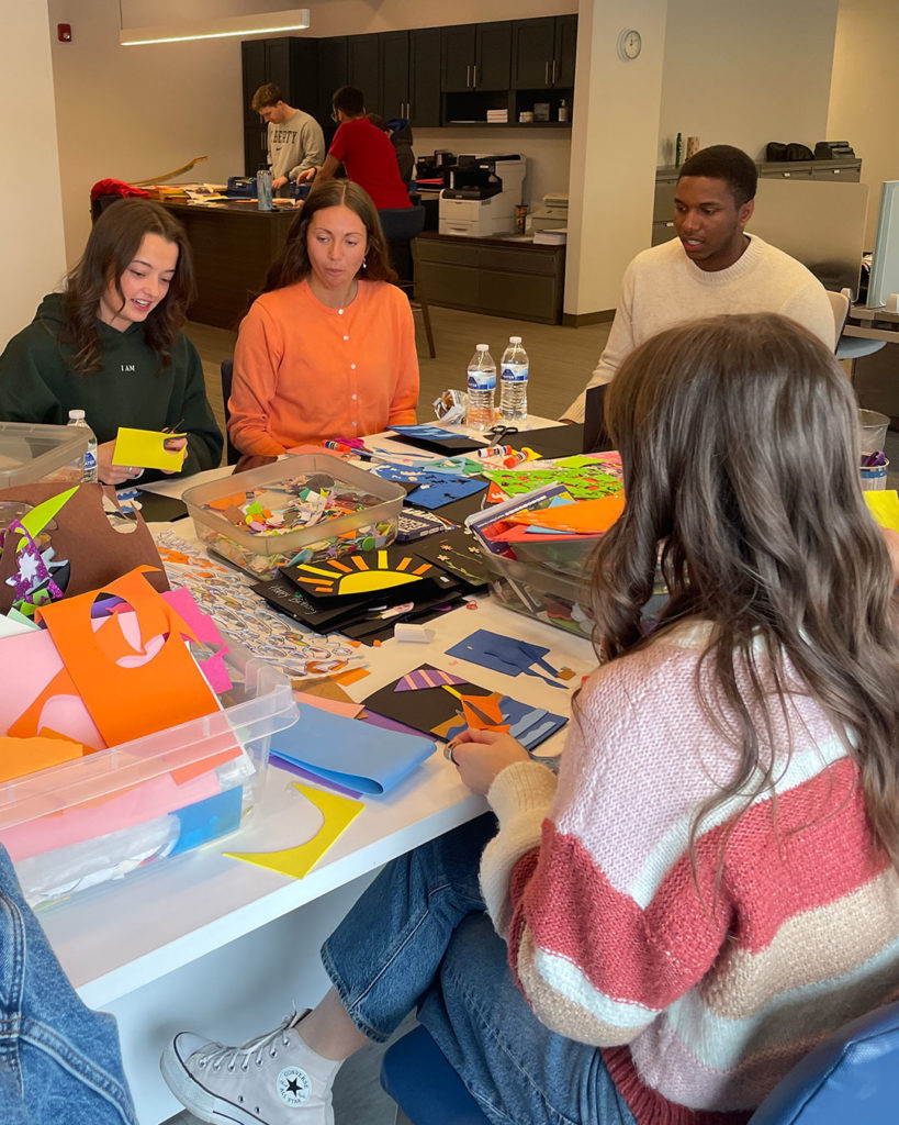 Volunteers from Mercy Road Church sit at the work table in the Family Resource Center and make cards.