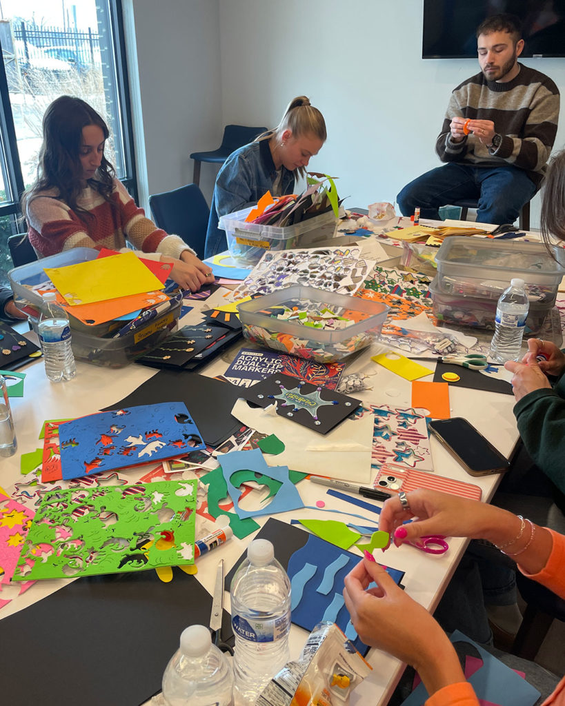 Volunteers from Mercy Road Church sit at the work table in the Family Resource Center and make cards.