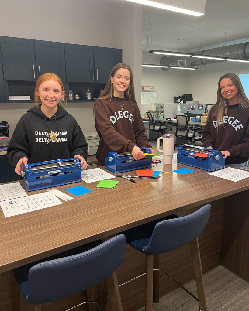 Three Delta Gammas make braille card inserts at the FRC.
